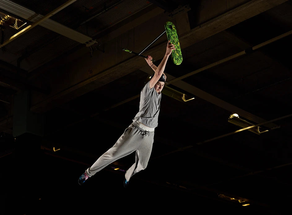 A rider performs a trick on the INDO PRO V2 Green Mamba trampoline trick scooter, capturing an exciting moment mid-air.
