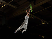A rider performs a trick on the INDO PRO V2 Green Mamba trampoline trick scooter, capturing an exciting moment mid-air.