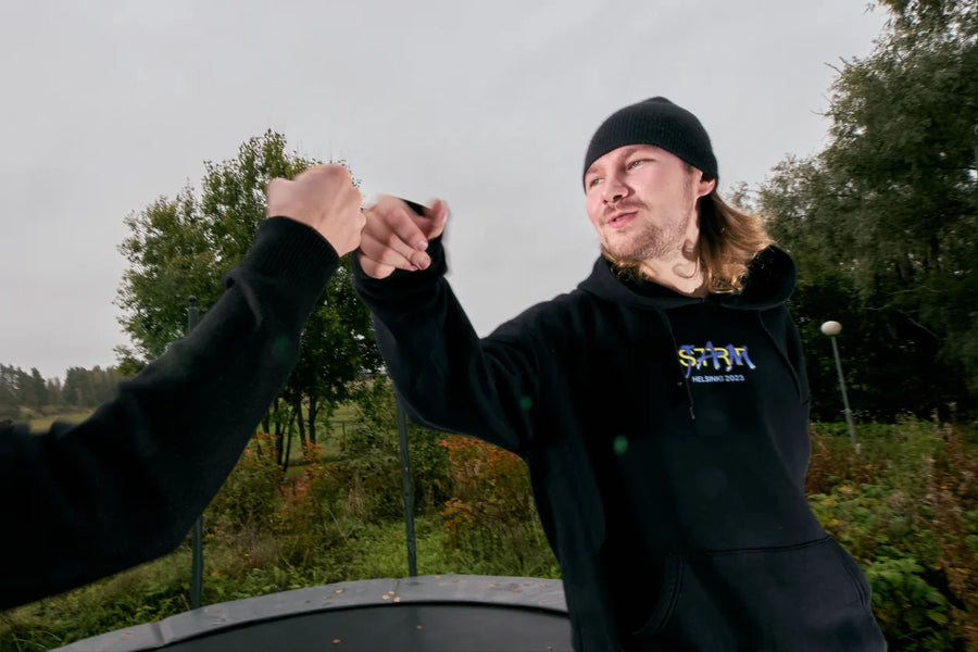 Two riders fist bump on a trampoline